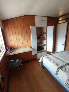 a bedroom with a bed and a wooden wall at Habitación privada en Puerto Varas in Puerto Varas