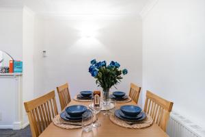 ein Esstisch mit blauem Geschirr und einer Vase mit blauen Blumen in der Unterkunft Cosy 2-Bed Maisonette in Ashford in Kennington + 10 Fotos