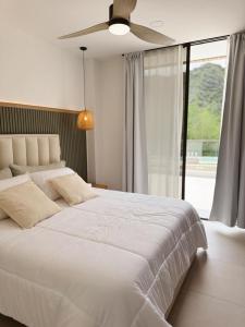 a bedroom with a white bed with a ceiling fan at KOA Villeta - Loft y terraza con vista a la montaña in Nimaima +31 photos