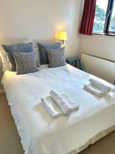 a large white bed with two towels on it at Island Retreat with HotTub in West Mersea