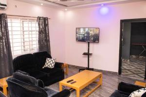 ein Wohnzimmer mit Sofas und einem Flachbildfernseher in der Unterkunft 2Bedroom Apartment at Pokuase in Ayaso