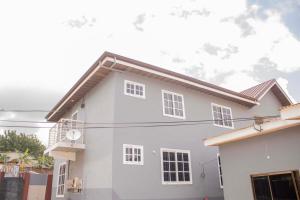 ein weißes Haus mit braunem Dach in der Unterkunft 2Bedroom Apartment at Pokuase in Ayaso