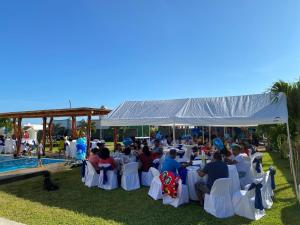 Eine Gruppe von Menschen sitzt auf Stühlen unter einem Zelt neben einem Pool. in der Unterkunft Beautiful Beach House in Barra de Coyuca