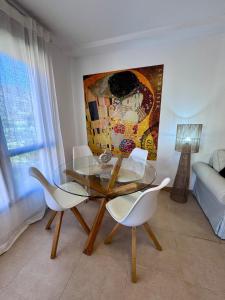 a dining room with a glass table and two white chairs at Sil&Sol in Arona