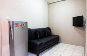 a black leather couch in a room with a refrigerator at Menteng Square Sahara II in Jakarta