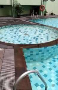 a large swimming pool with blue tiles in a building at Menteng Square Sahara II in Jakarta