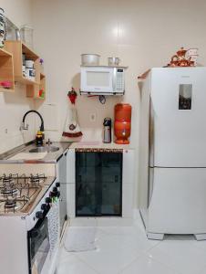 a white kitchen with a stove and a refrigerator at Casa Ampla com Garagem Ar-condicionado no Centro in Ananindeua