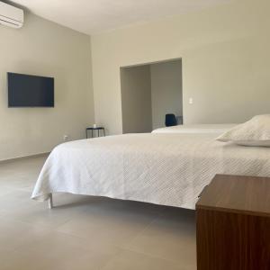 a bedroom with a white bed with a tv on the wall at MA1100 loft in Colima