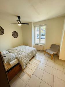 ein Schlafzimmer mit einem Bett und einem Stuhl und einem Fenster in der Unterkunft Le Siesskass in Gunsbach