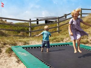 een jongen en een meisje die op een trampoline spelen bij 6 person holiday home in Ringkøbing in Ringkøbing