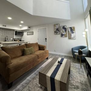 een woonkamer met een bruine bank en een tafel bij 3BD DT Dallas l FIFA WORLD CUP READY l 5 Min from Love Field in Dallas