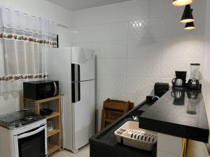 Il comprend une cuisine équipée d'un réfrigérateur blanc et d'une cuisinière. dans l'établissement Casa de praia em Cabo Frio, à Cabo Frio
