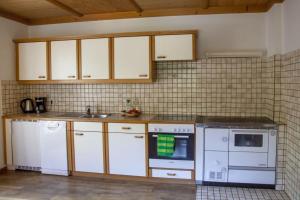 a kitchen with white appliances and a tile wall at Achthütte in Grossarl