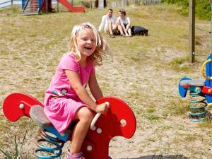 Una niña pequeña sentada en un caballito de juguete en un parque infantil en 8 person holiday home in Ringkøbing, en Ringkøbing