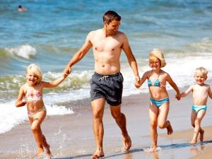 Un hombre y dos niños caminando por la playa en 8 person holiday home in Ringkøbing, en Ringkøbing