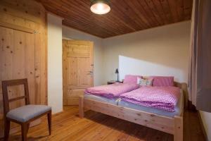 a bedroom with a bed with pink sheets and a chair at Chalet Unterleming in Angerberg