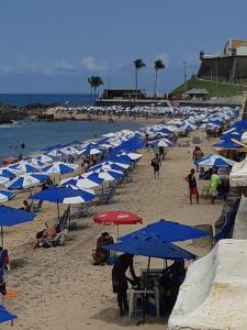 Un grupo de sombrillas azules y blancas en una playa. en TÔ em casa Barra Porto, en Salvador
