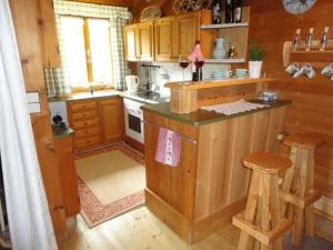 a kitchen with wooden cabinets and a counter with stools at Neukam Hütte in Mühlbach am Hochkönig +5 photos