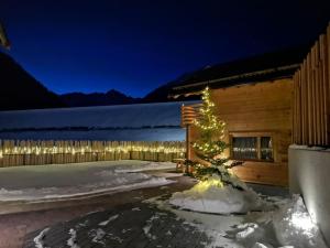 Ein Weihnachtsbaum im Schnee vor einer Hütte in der Unterkunft Chalets Lagaun in Villetta