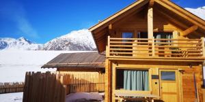 Eine Blockhütte vor dem Hintergrund schneebedeckter Berge in der Unterkunft Chalets Lagaun in Villetta