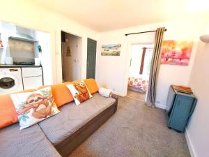 a living room with a couch with orange pillows at The Wee Nest in Largs - One-Bedroom Ground Flat in Largs
