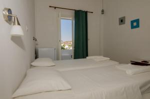 two beds in a white room with a window at Ios Plage in Mylopotas