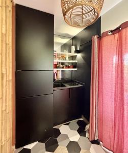 a kitchen with black walls and a red curtain at Village Soleil in Îlet à Boissard