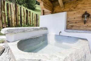 a stone bathtub in a backyard with a wooden fence at Chalet Almrausch in Unterberg