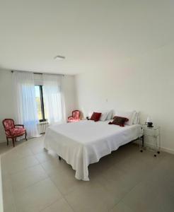 1 dormitorio blanco con 1 cama grande y 2 sillas en Spacious and comfortable apartment for 4 people, en El Durazno 4 fotos más