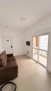 a living room with a couch and a sliding glass door at palmas beach in Governador Celso Ramos