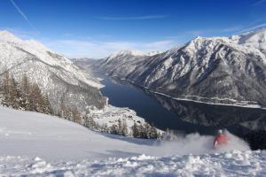 a person riding a snowboard down a snow covered mountain at Alpen-Chalets Achensee in Häusern