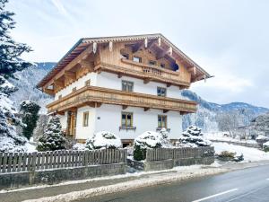 a house with a wooden roof in the snow at Appartement Aschau in Aschau