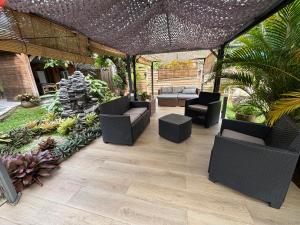 a patio with couches and chairs under a roof at Chambre zen & bien-être à 5 mn de la Galléria in Le Lamentin