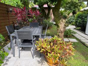 a wooden table and chairs in a garden with plants at Chambre zen & bien-être à 5 mn de la Galléria in Le Lamentin