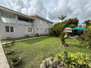 a backyard of a house with a lawn with plants at Chambre zen & bien-être à 5 mn de la Galléria in Le Lamentin