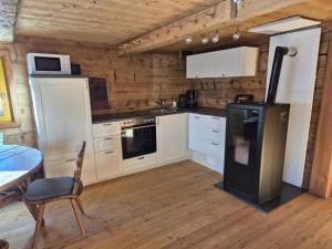 a kitchen with white cabinets and a black refrigerator at Achtchalet in Grossarl