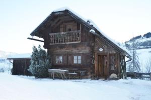 a log cabin in the snow with a bench in front at Hexenhäuschen in Bachwinkl
