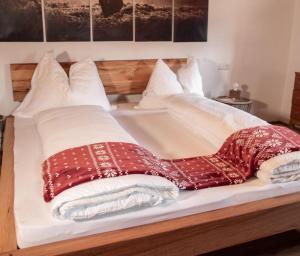 a bed with white pillows and red and white blankets at Artlieb Hütte in Maschl