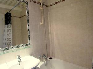 a bathroom with a sink and a tub and a mirror at Hôtel du Square d'Anvers in Paris