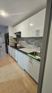 a kitchen with white cabinets and a sink at Casa Galena in Corralejo