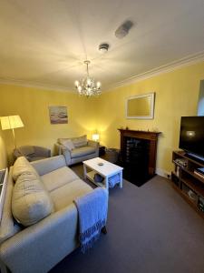 a living room with a couch and a tv at Cosy Cottage on the Whisky Trail in Haugh of Glass