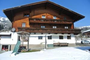 a large building with a wooden roof in the snow at Bauernhaus Hollersbach in Hollersbach im Pinzgau
