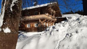 a log cabin with a pile of snow in front of it at Bauernhaus Brixen in Bichling