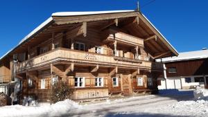 a large wooden building with snow on the ground at Bauernhaus Brixen in Bichling