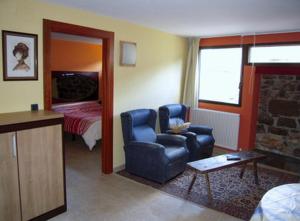 una sala de estar con una silla azul y un dormitorio en Casa Rural Apartamento El Chaveto, en Herreros