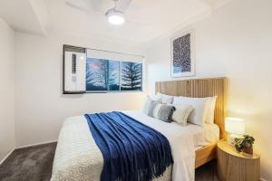 een slaapkamer met een groot bed met een blauwe deken bij Dwell at 38, Oceanfront Apartment in Bargara +25 foto's