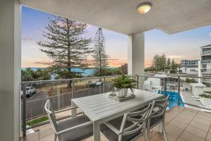 een eetkamer met een tafel en stoelen op een balkon bij Dwell at 38, Oceanfront Apartment in Bargara