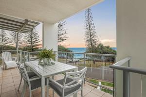 een balkon met een tafel en stoelen en de oceaan bij Dwell at 38, Oceanfront Apartment in Bargara