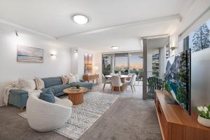 een woonkamer met een blauwe bank en een tafel bij Dwell at 38, Oceanfront Apartment in Bargara