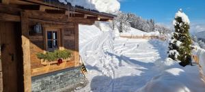 a snow covered road next to a cabin at Faschinghütte in Mühlbach am Hochkönig